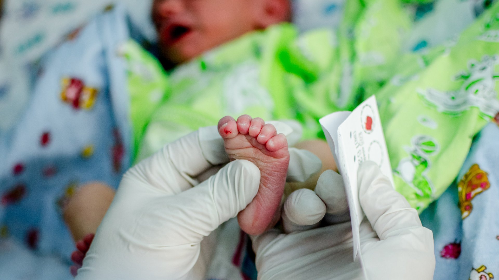 Lekarka wykonuje badania przesiewowe na stopie dziecka