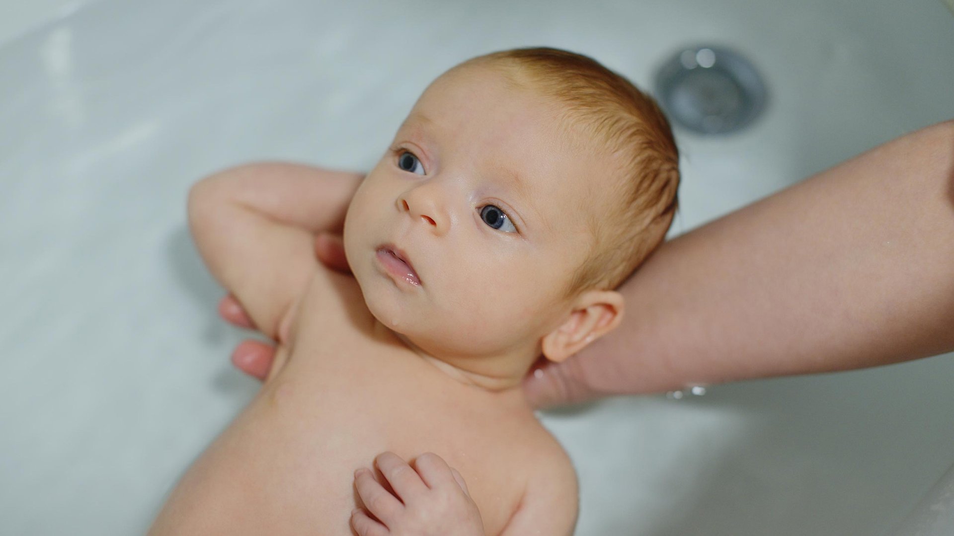 Rodzic myje noworodka w wannie