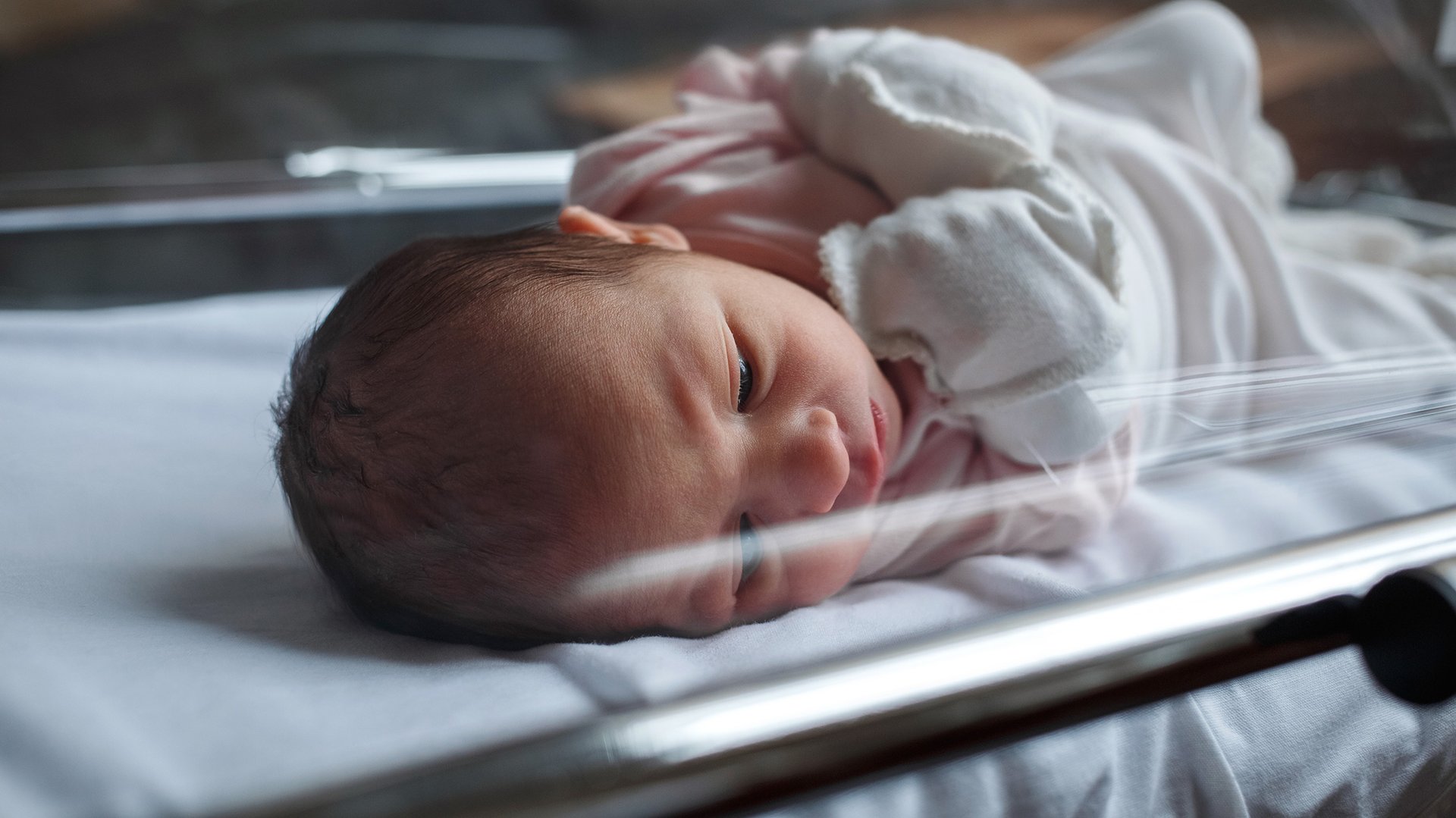 Noworodek lezy zmeczony w szpitalnym kojcu