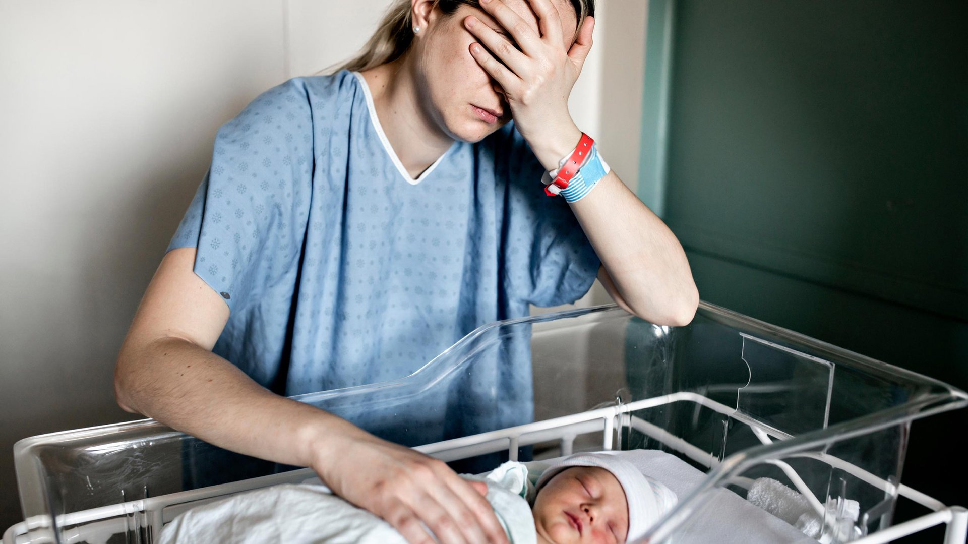 Zmartwiona kobieta kladzie reke na dzecku lezacym w szpitalnym lozku