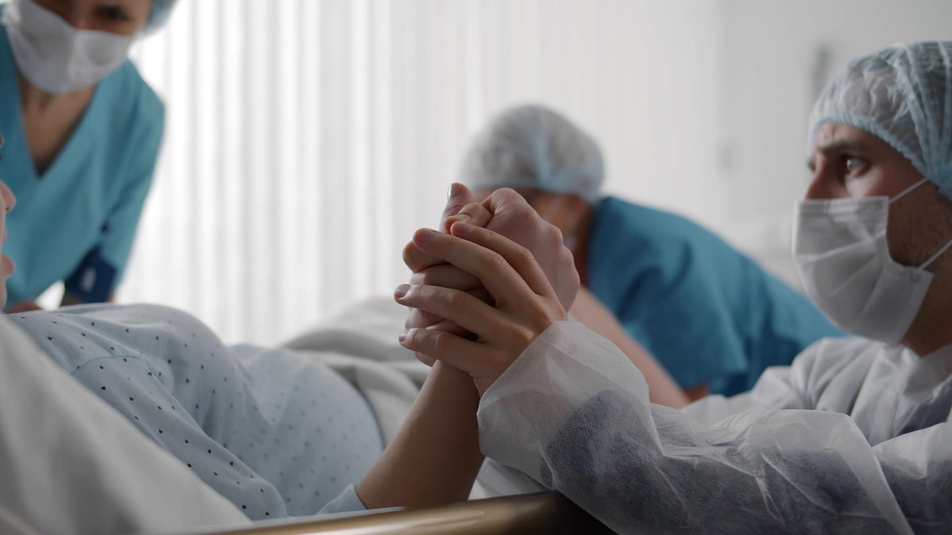 Mezczyzna trzyma za reke kobiete w czasie porodu