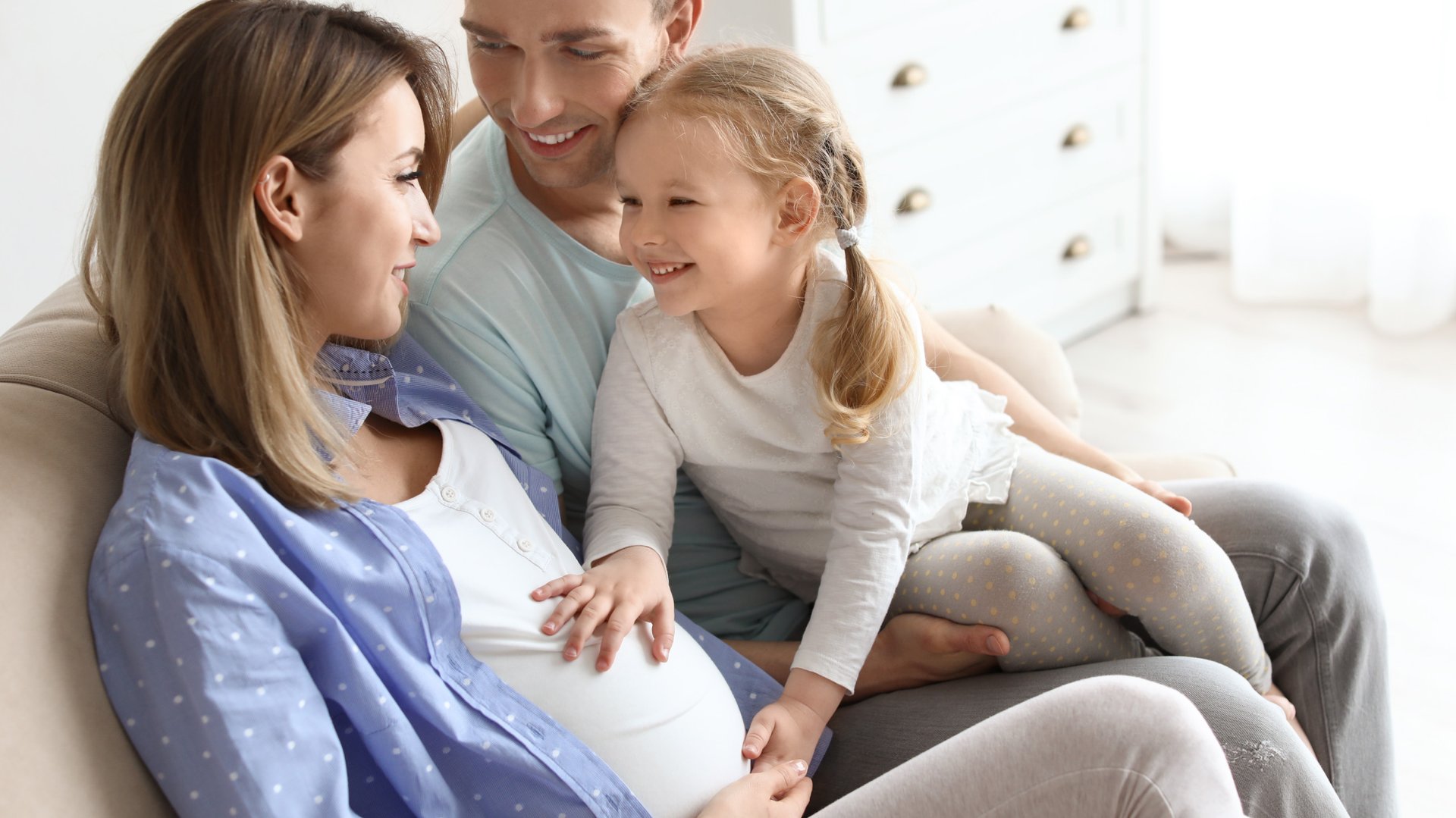 Dziecko i tata dotykaja brzucha kobiety w ciazy