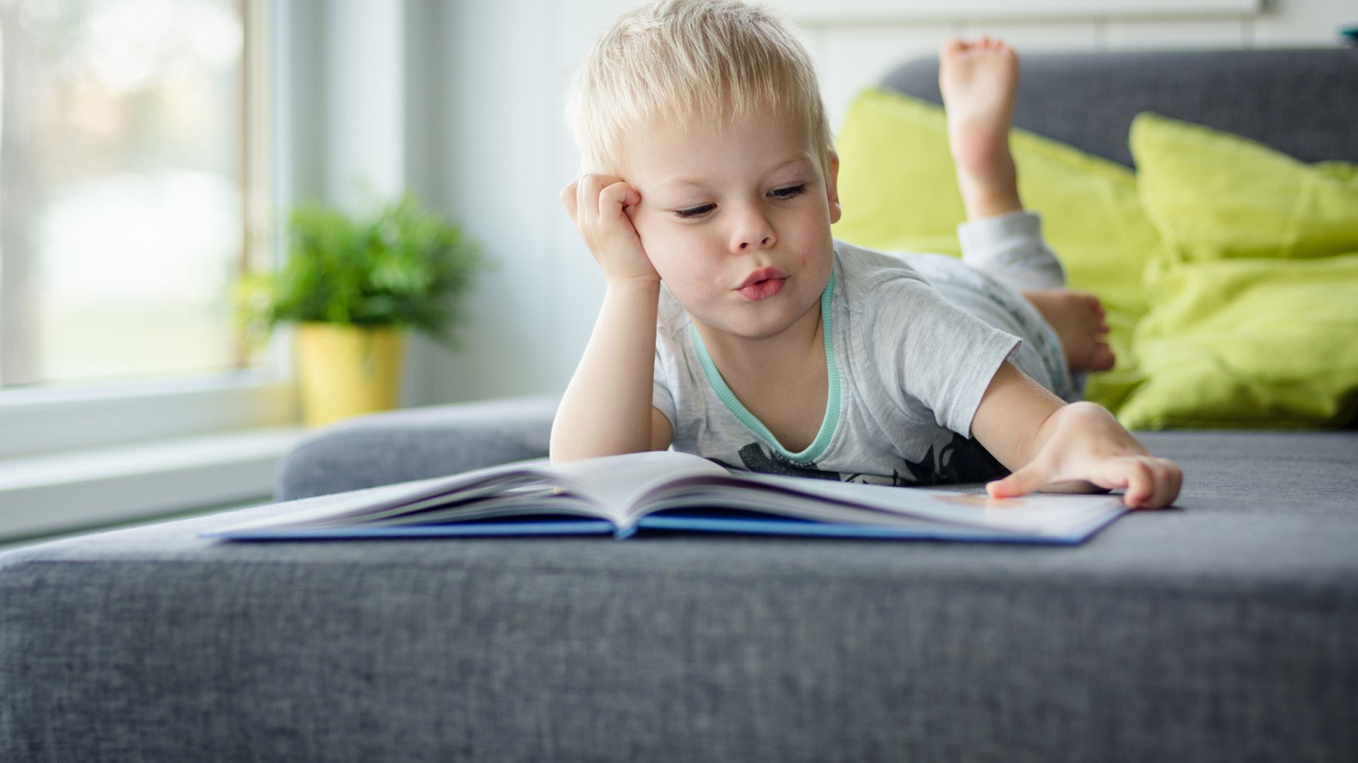 Dziecko czyta samodzielnie ksiazke na lozku