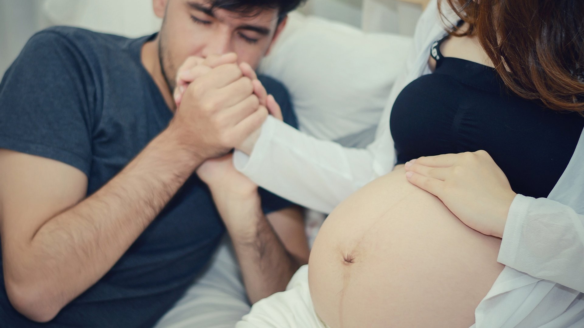 Mezczyzna wspiera kobiete w ciazy calujac ja w reke