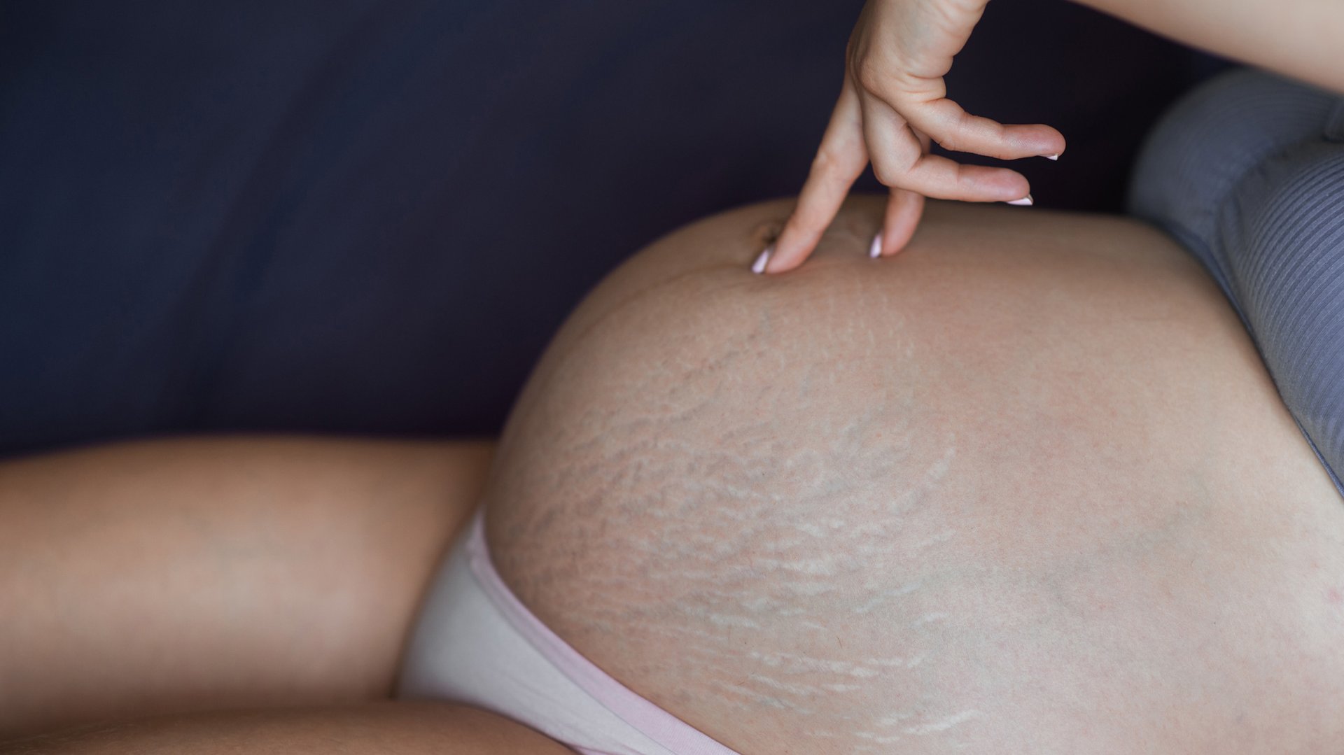 Kobieta dotyka dwoma palcami ciazowego brzucha