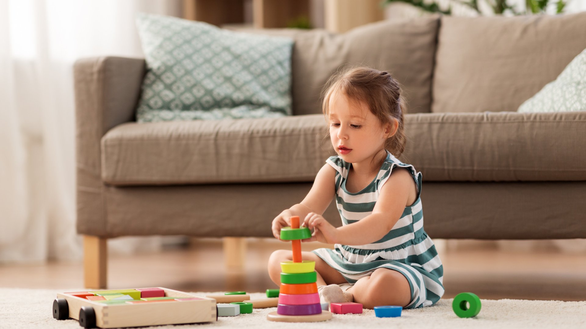Mała dziewczynka bawi sie zabawkami na dywanie