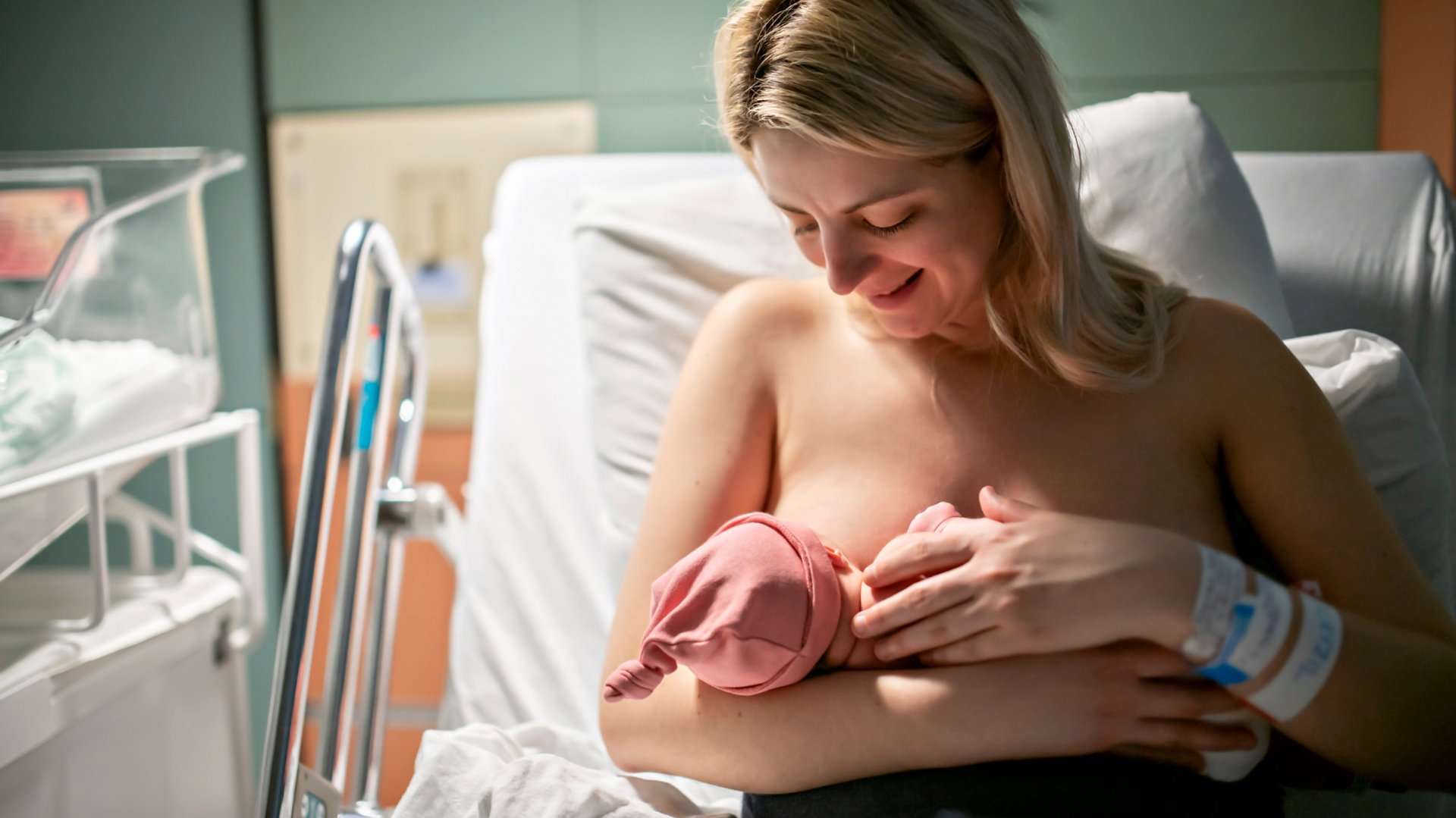 Kobieta po cesarskim cieciu karmi noworodka w szpitalu