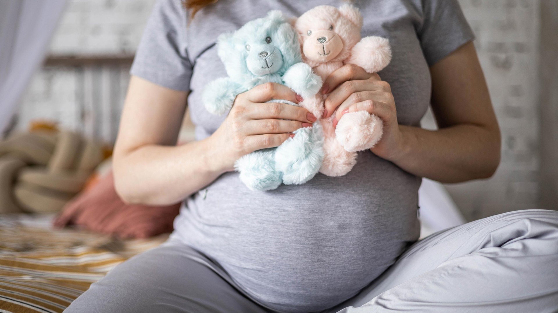 Kobieta w ciazy trzyma w reku dwa misie