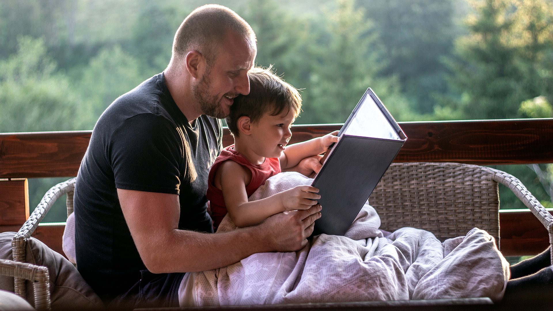 Tata uczy syna czytac na balkonie