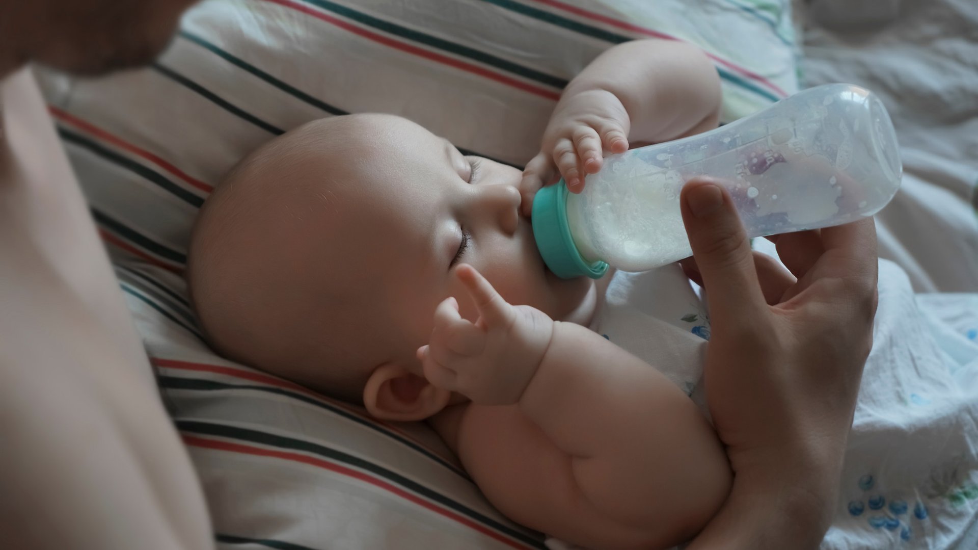 Rodzic karmi lezace dziecko butelka z mlekiem