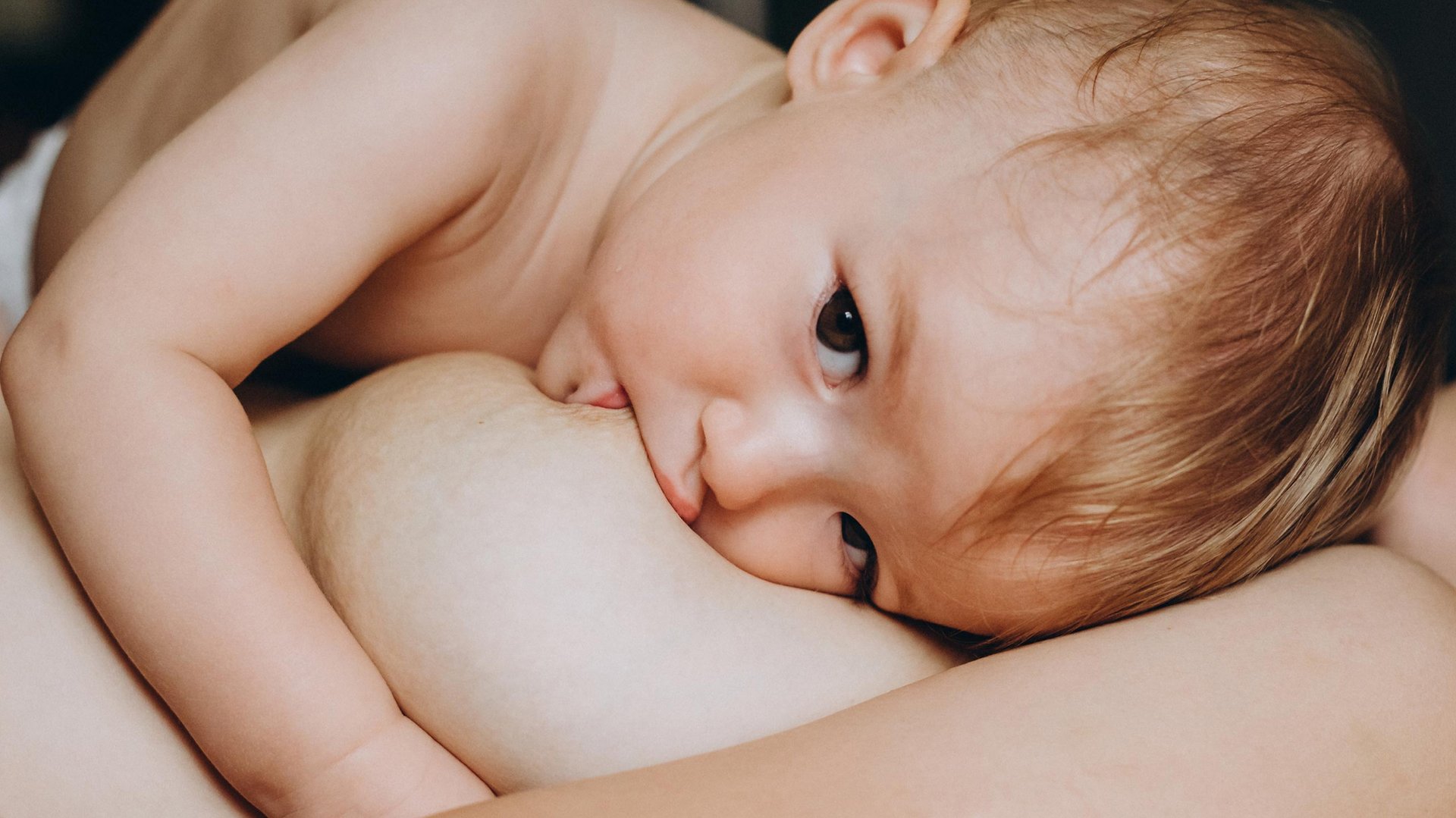 Dziecko lezy na mamie pijac z jej piersi mleko