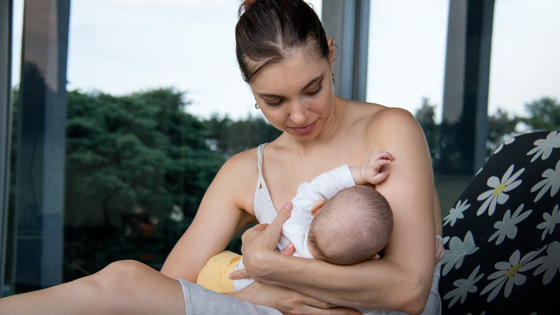 Kobieta karmi dziecko piersia siedzac na lezaku