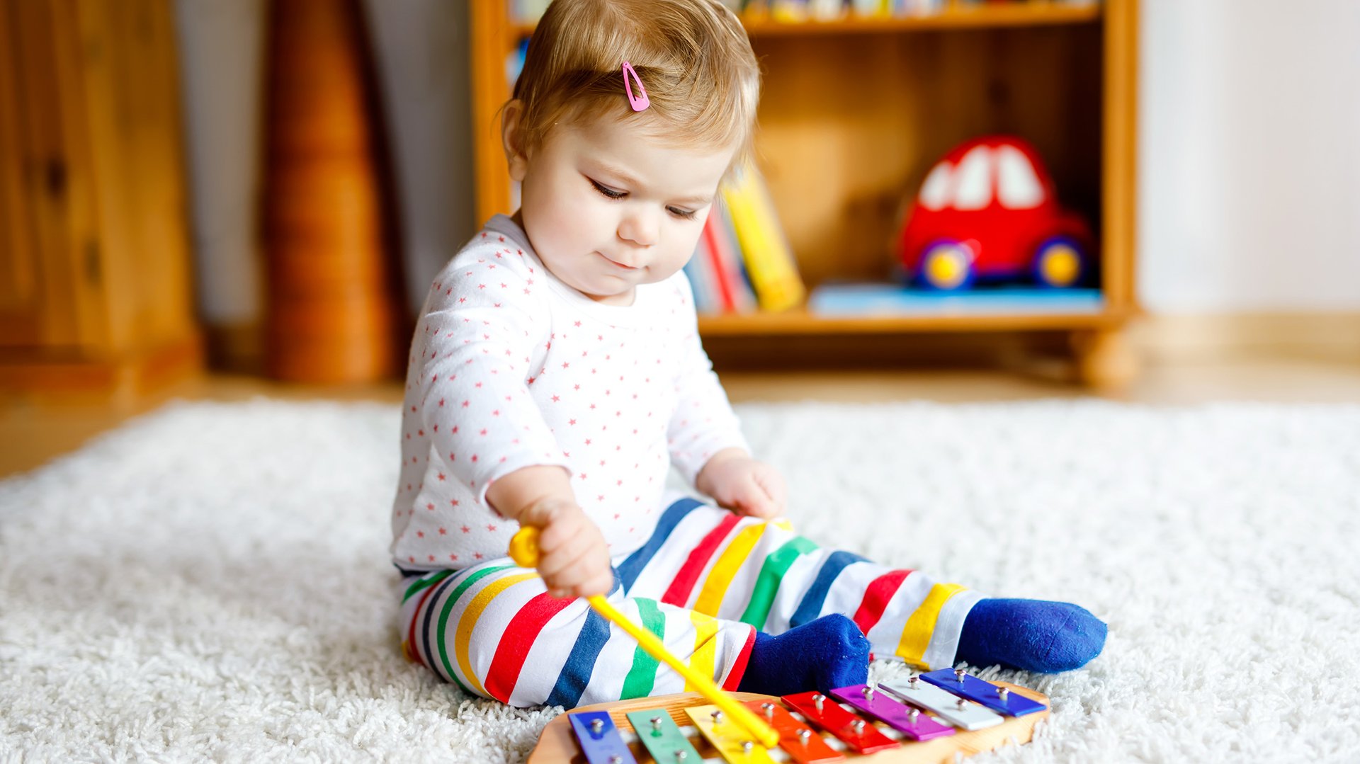 Dziecko uczy się gry na cymbalakach siedzac na dywanie