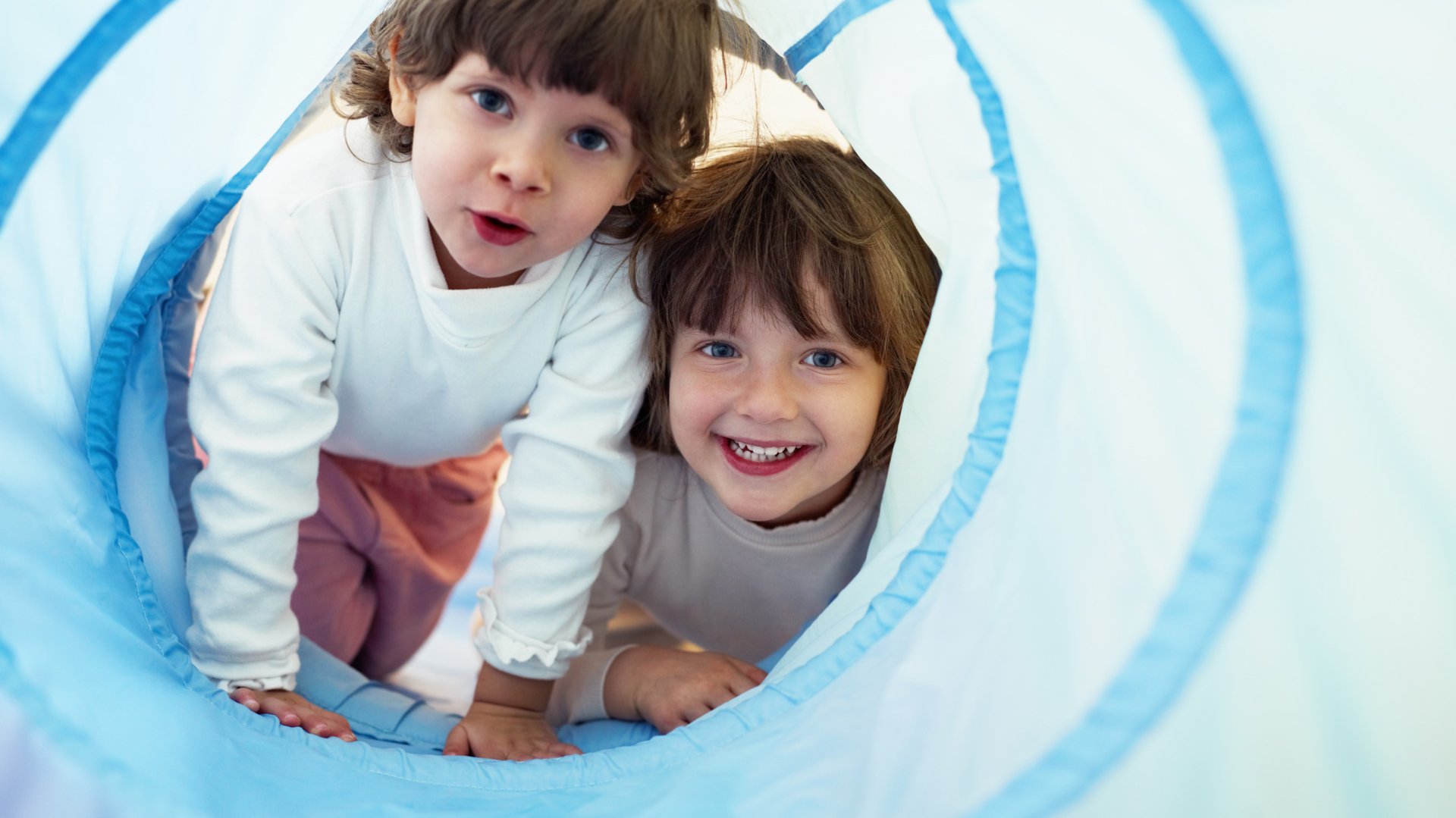 Dwoje dzieci bawi się w niebieskim tunelu