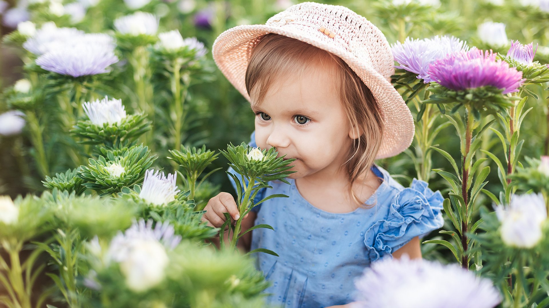 Dziecko wacha kwiatki w ogrodzie pelnym roslin
