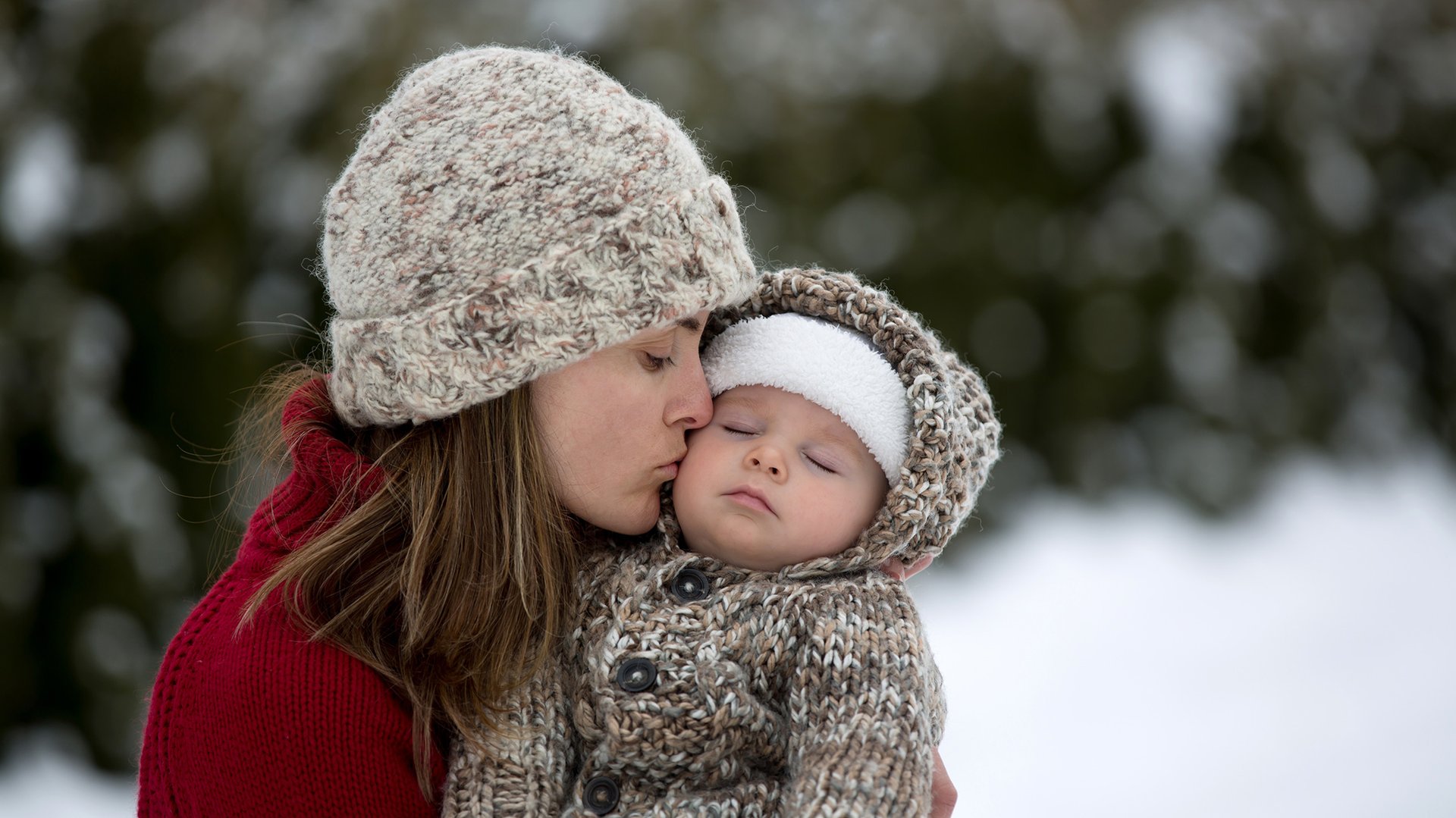 Mama caluje dziecko ubrane w cieple ubrania zimowe