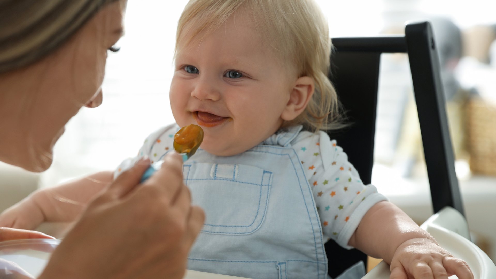 Dziecko usmiecha sie widzac zblizajaca sie lyzeczke z jedzeniem